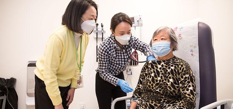 Yoonmee Joo (left), assistant clinical professor in the Adult Gerontology Primary Care Nurse Practitioner specialty, precepts master's student Ellen Park Chang as she provides care to patient Lini Xu at the Center for Elders Independence in Oakland, California. (Photo credit: Elisabeth Fall)