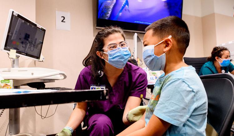 UCSF School of Nursing MEPN student Carly Hwang administers a COVID-19 vaccine to Marcus Reyes, 10, during a clinic at UCSF Benioff Children's Hospital Oakland on Dec. 11, 2021 (Photo by Noah Berger).