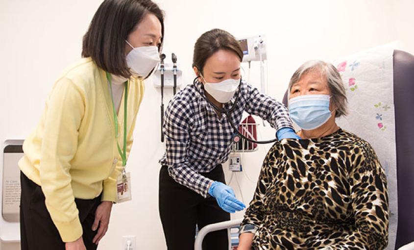 Yoonmee Joo (left), assistant clinical professor in the Adult Gerontology Primary Care Nurse Practitioner specialty, precepts master's student Ellen Park Chang as she provides care to patient Lini Xu at the Center for Elders Independence in Oakland, California. (Photo credit: Elisabeth Fall)