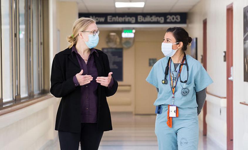 FirstGenRN Director Laura Wagner, left, speaks with Jacqueline Carrillo as they walk down the hall at the San Francisco VA Medical Center, where Carrillo is completing a residency program. (Elisabeth Fall Photography) 