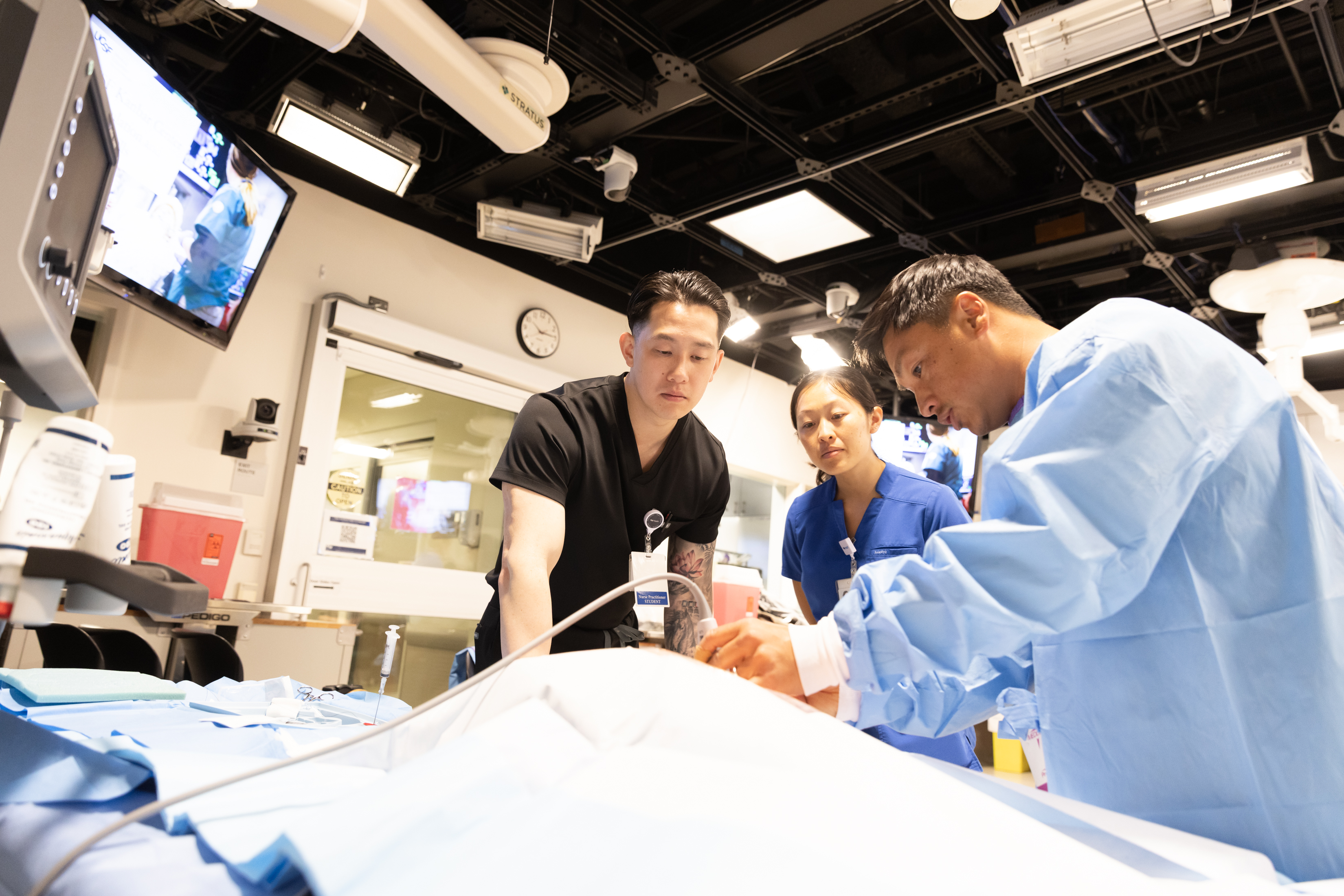 Two students watch an instructor demonstrate a critical care procedure