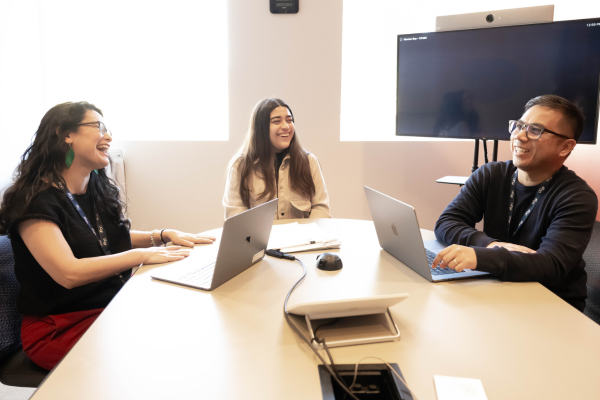 Three people talk at a table.
