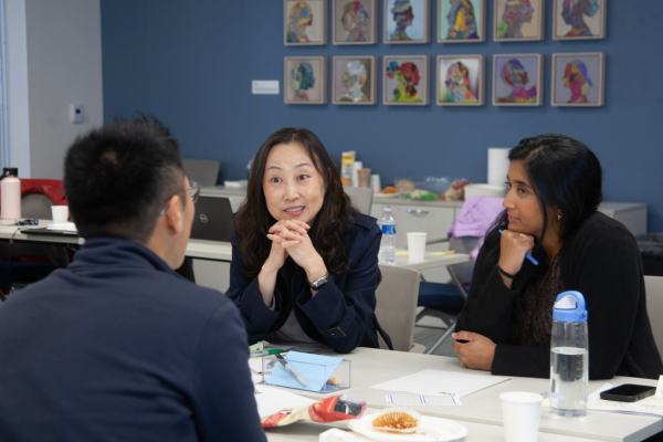 Three people talk at a table.