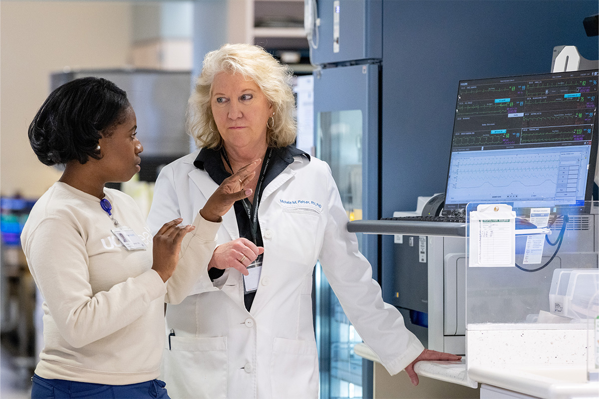 Michele Pelter (right) speaks with nurse Adrienne D. Gorrell while looking at data from a heart monitor located on the floor of the cardiac ICU.