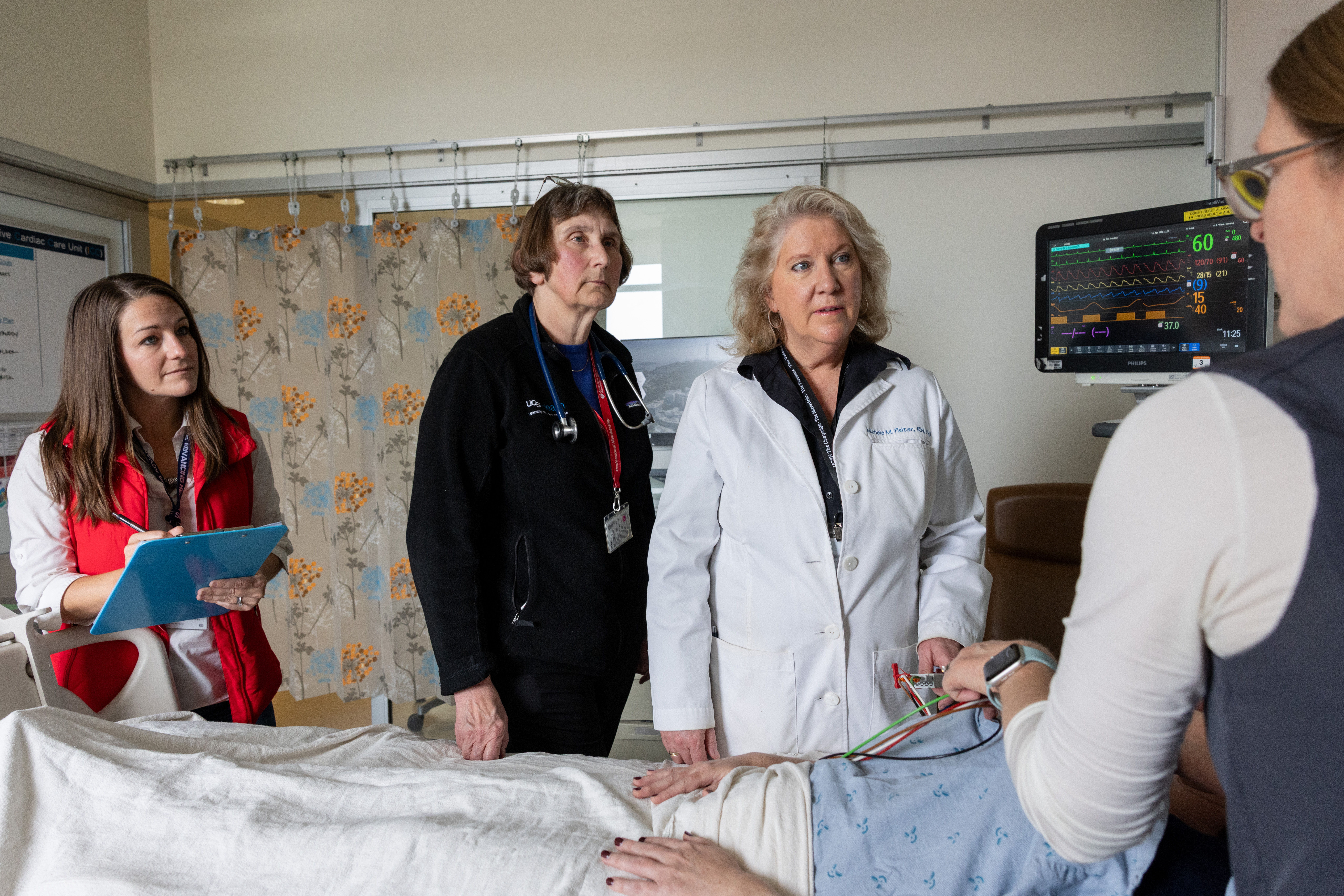 Four health care providers and a patient in a hospital room in the cardiac ICU.