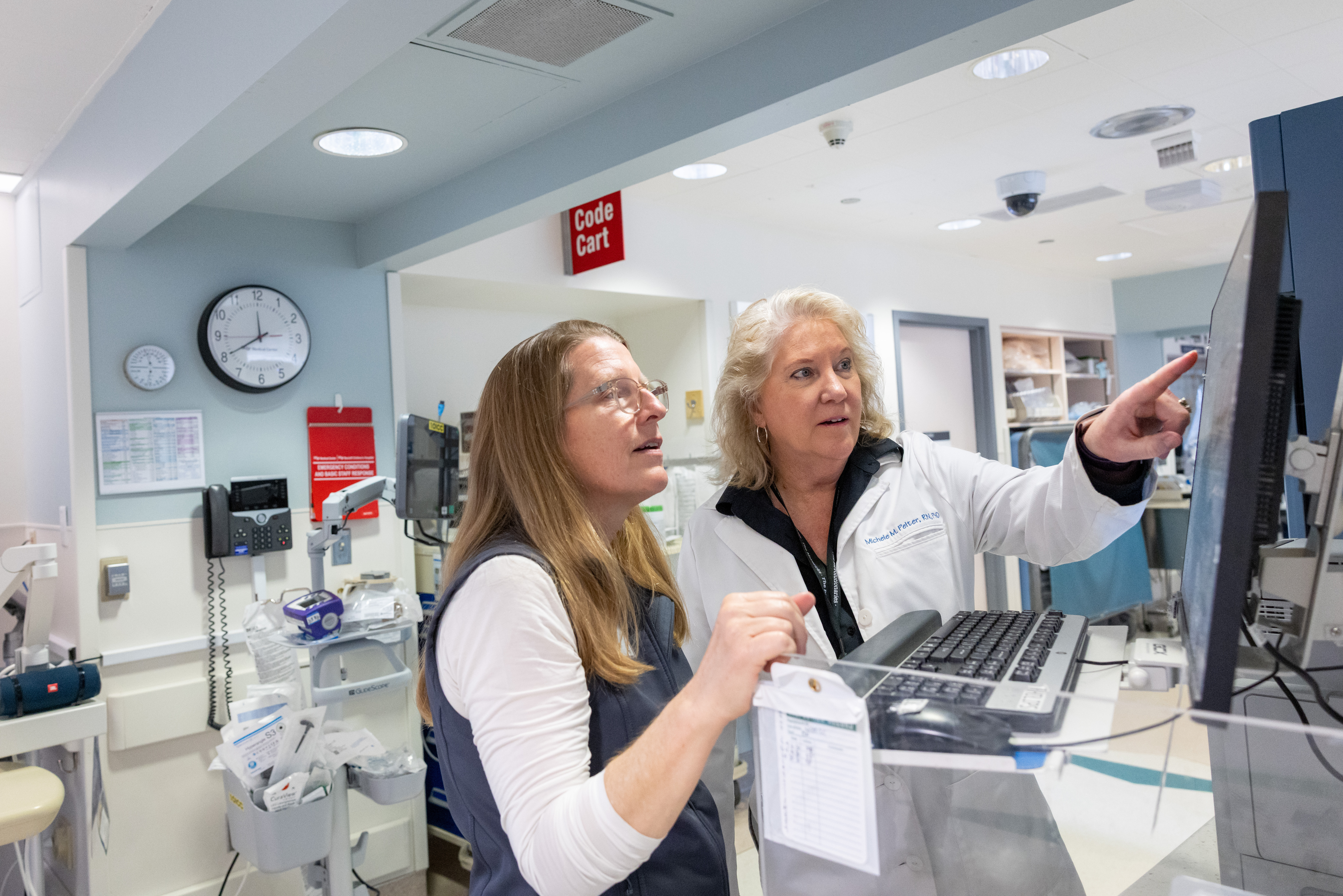 Michele Pelter (right) and a nurse review data on a screen located on the cardiac ICU floor.