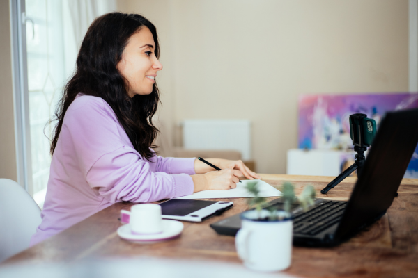 Person sits at table working on laptop.