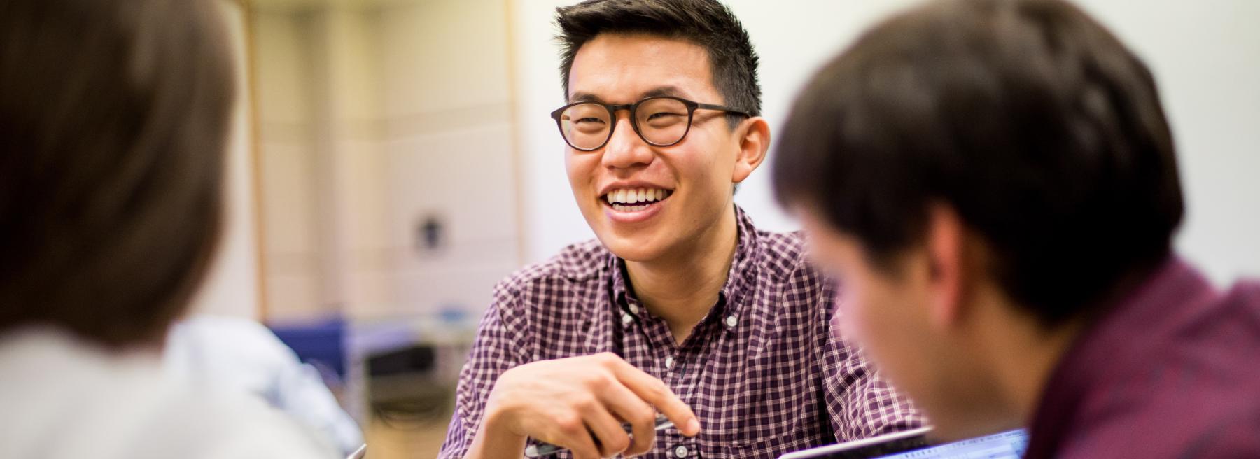 Student Sits At Table Talking To Two Other Students