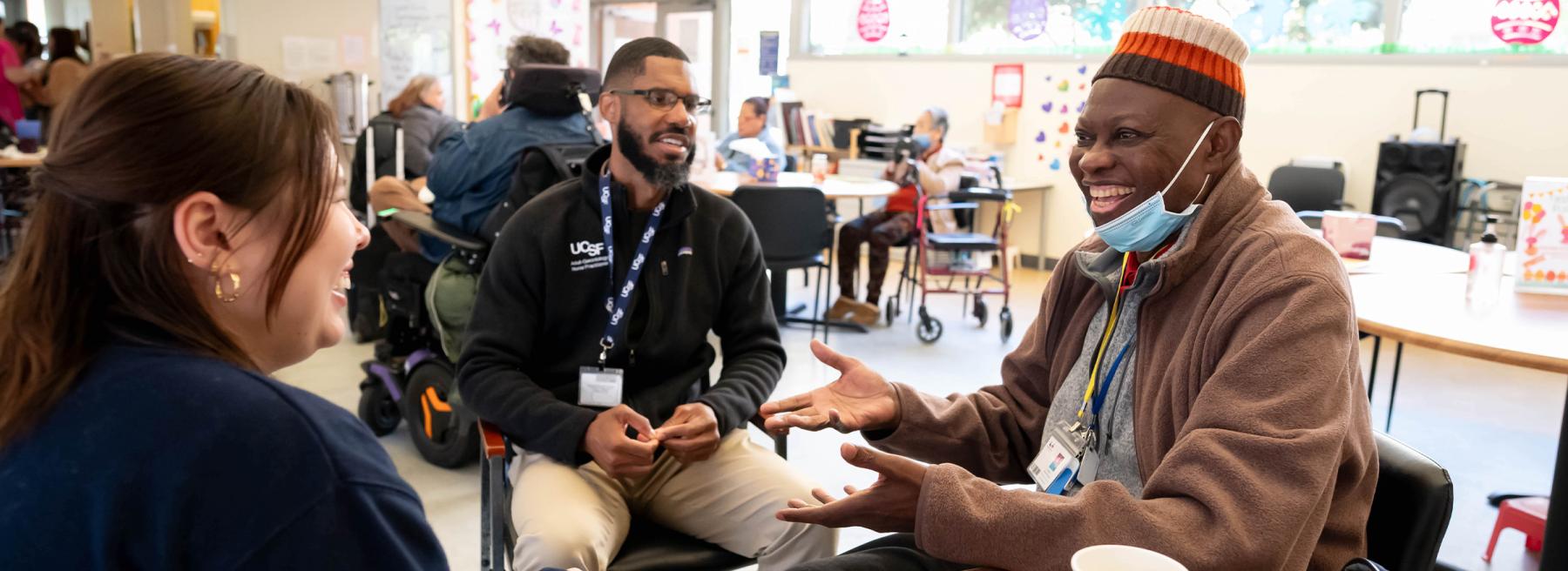 Three people sit in a circle talking and laughing.
