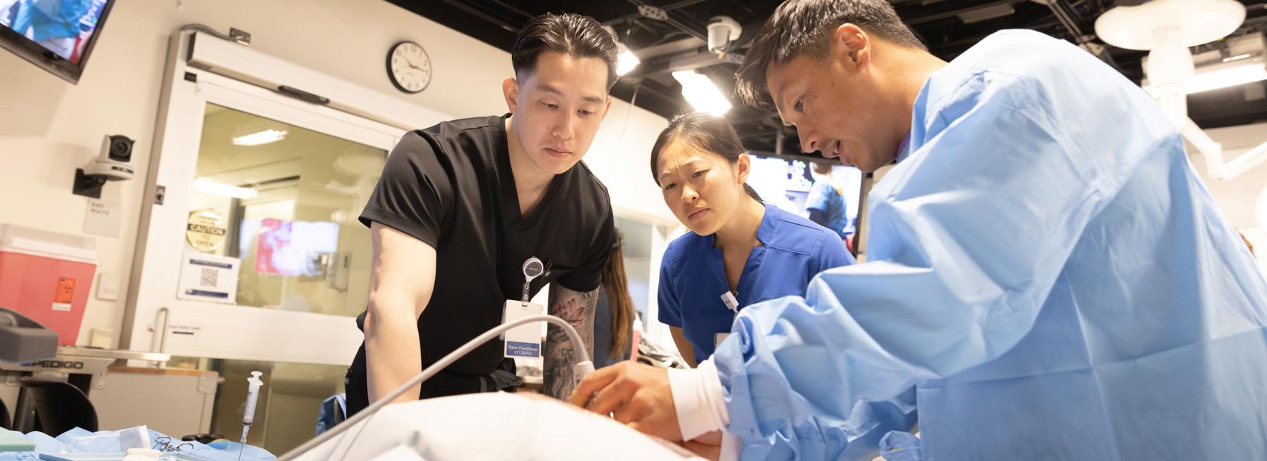 Two students and a faculty member practice clinical skills in the simulation lab.
