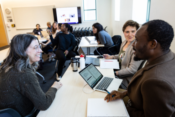 Three students sit in a classroom and talk.