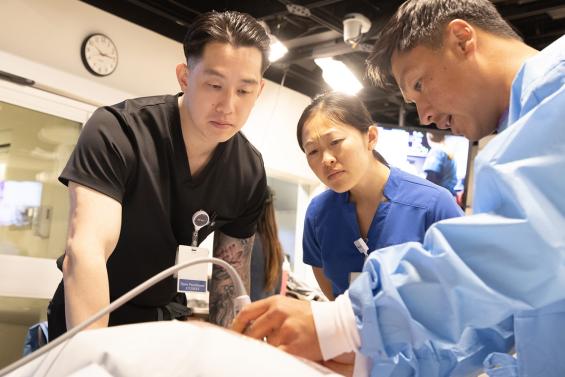 Two students and a faculty member practice clinical skills in a simulation lab.