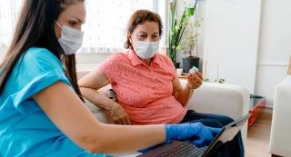 Two people sitting on couch looking at a computer.