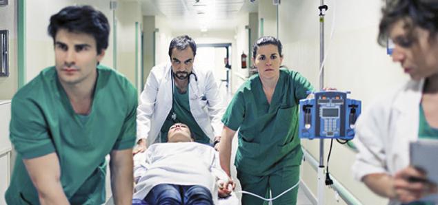 Nurses move patient on a hospital gurney.