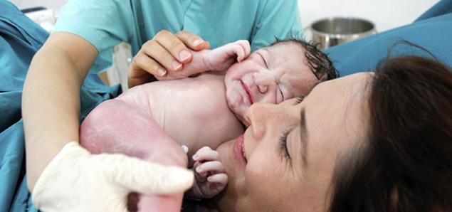 A nurse places an infant on its mother's chest.
