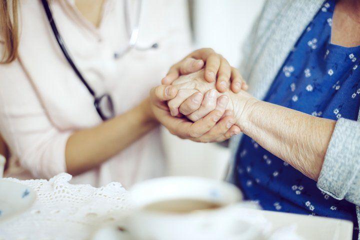 Elderly woman holding hand with doctor