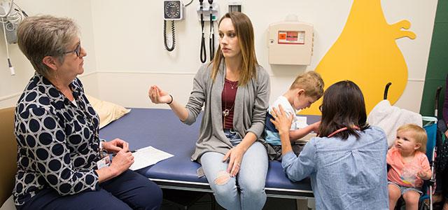 As Barbara Bratton (left) speaks with the patient’s mother in the UCSF LIFE Clinic, pediatric surgeon Lan Vu examines the child (photos by Elisabeth Fall).