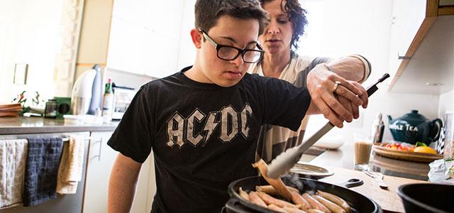 Seventeen-year-old Eli Cooper gets a cooking lesson from his mother, Jennifer (photo by Elisabeth Fall).