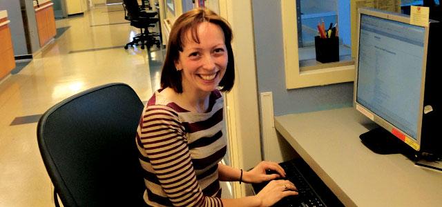 Jennifer Baird sits in front of a computer, typing on a keyboard. 