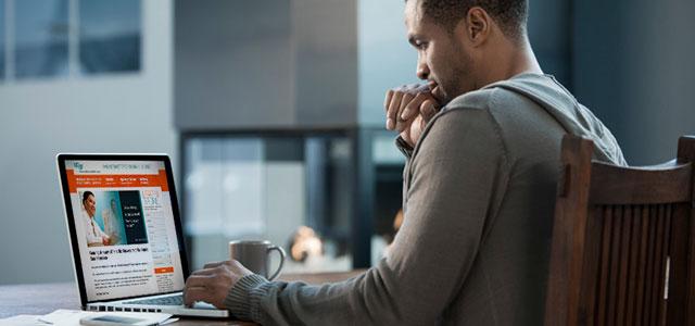 Person sits at desk, looking at computer screen.