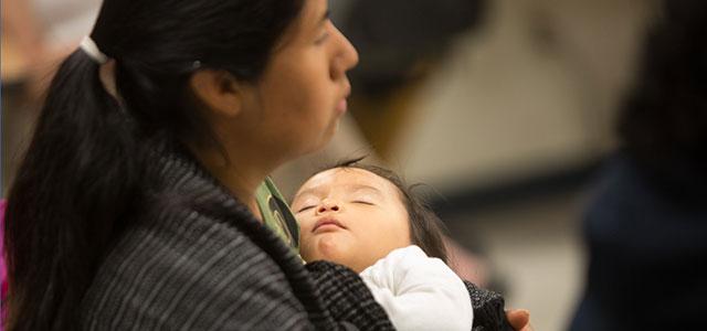 A mother holds a sleeping baby.