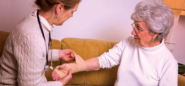 Nurse wraps wrist of patient with bandage.