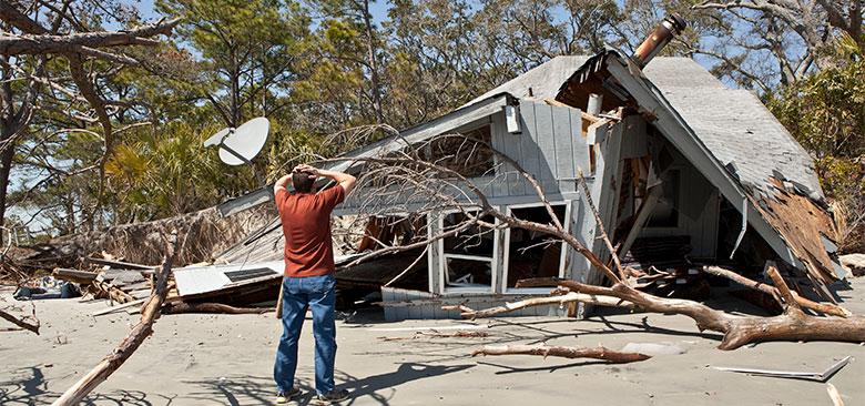 Person looks at home that has been destroyed in a natural disaster.