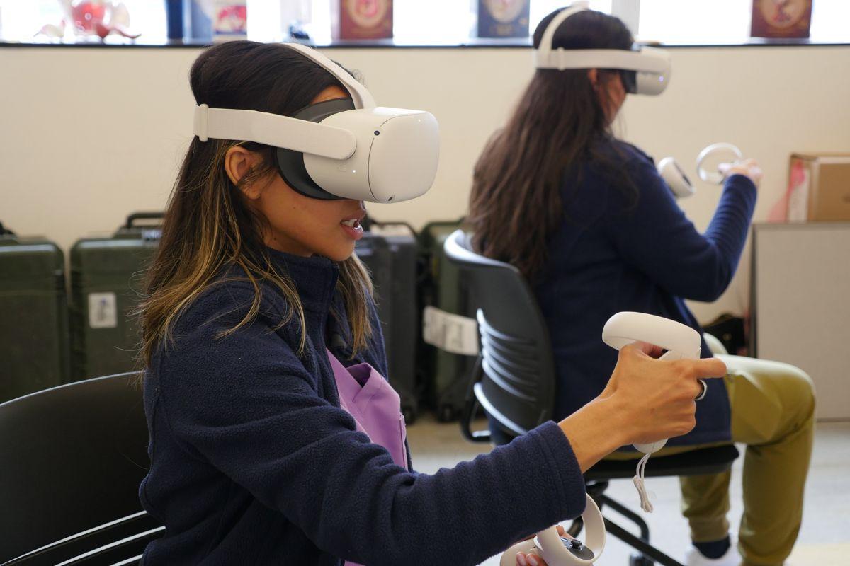 Two students wear virtual reality headsets while sitting in a classroom 