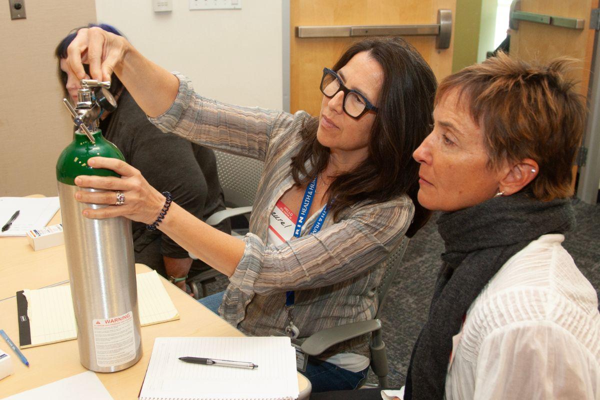 Two workshop participants check an oxygen tank's level.