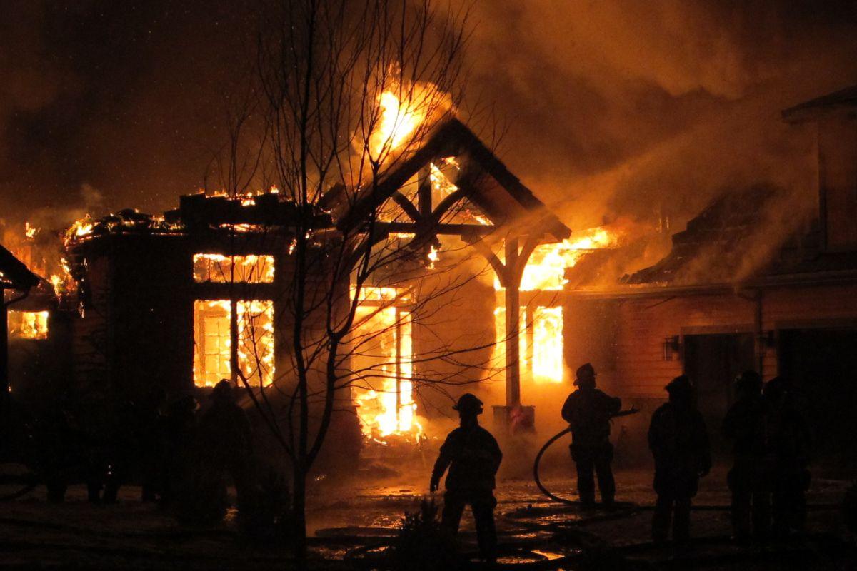 Firefighters spray water on a house that is on fire.