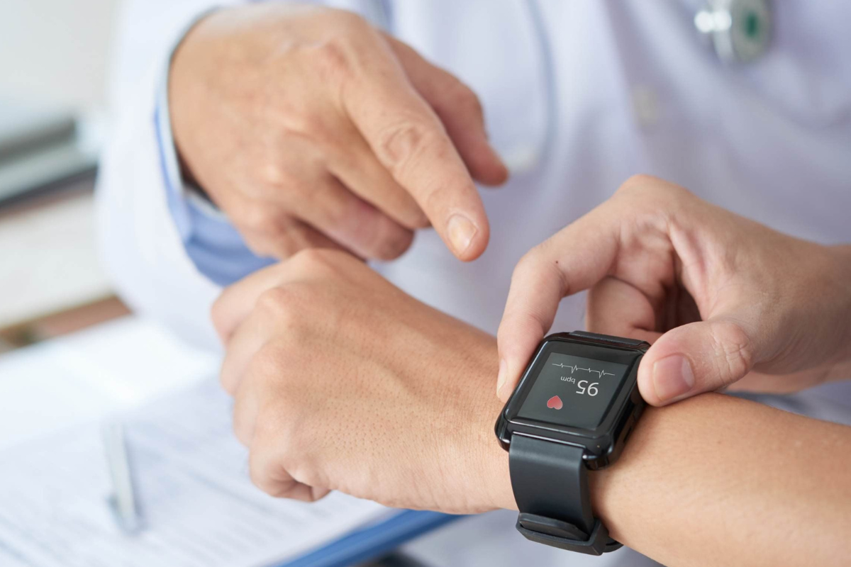 Healthcare provider points at someone's wrist that is adorned with a wearable fitness tracker.