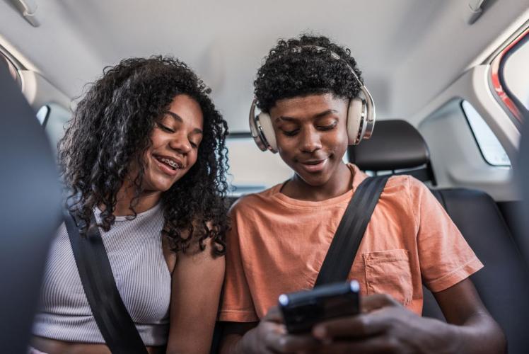 Teenagers sitting in car, looking at phone