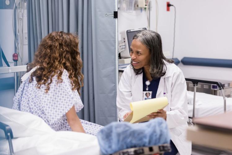 Nurse practitioner sits and talks to a patient in the emergency room.