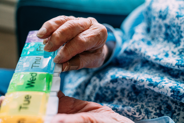 Hands holding colorful pill box.