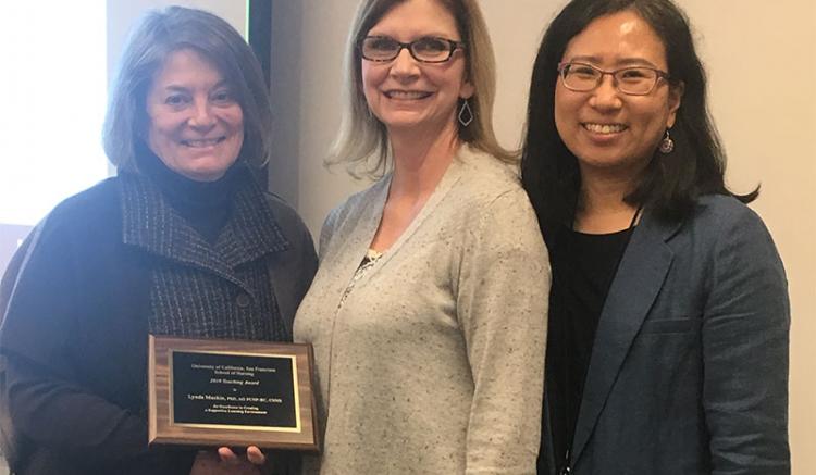 Lynda Mackin (center) is honored with an award for Excellence in Creating a Supportive Learning Environment. She is pictured with Dean Catherine L. Gilliss (left) and Soo-Jeong Lee, chair of the Faculty Council.
