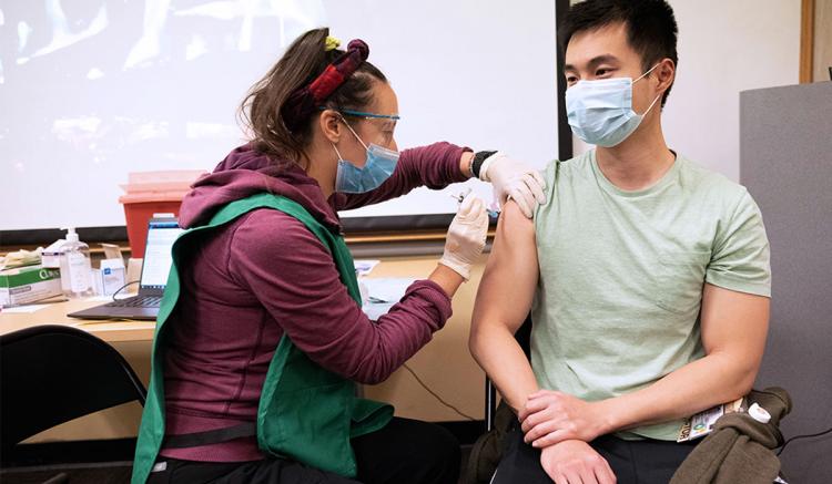 Anna Weissman (left), master's student in the UCSF School of Nursing, administers the COVID-19 vaccine to Kaiwen Sun, MD, right, resident physician in the UCSF Department of Medicine, at UCSF's Parnassus clinic in December 2020.