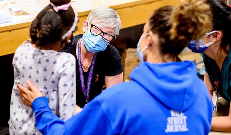 UCSF School of Nursing professor Maureen McGrath, MS, PNP, speaks with Bisani Crofton, 6, as she receives a COVID-19 vaccine during a clinic at UCSF Benioff Children's Hospital Oakland on Dec. 11, 2021. (Photo by Noah Berger)