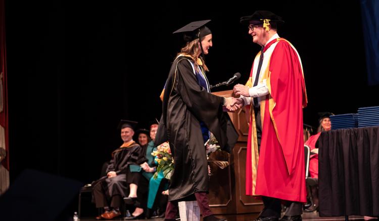Heather Coyne, a master's graduate, shakes the hand of UCSF Chancellor Sam Hawgood at Commencement.