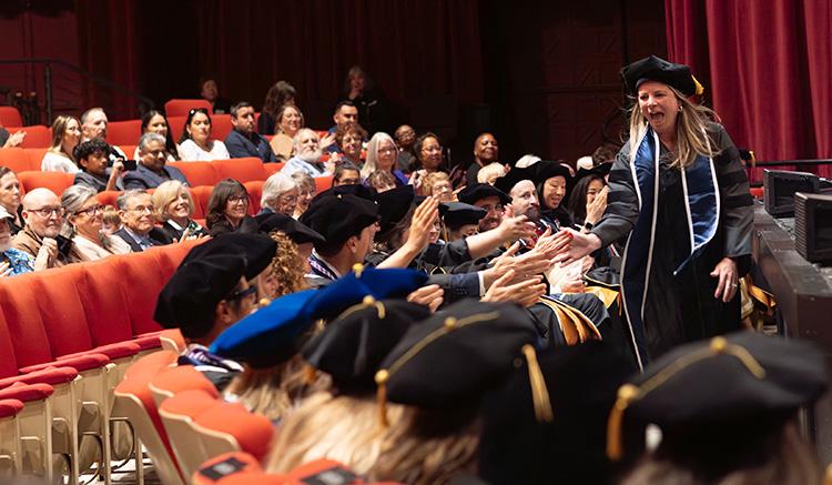 Kay Burke high-fives her classmates at the 2026 UCSF School of Nursing Commencement in the Palace of Fine Arts Theatre. 