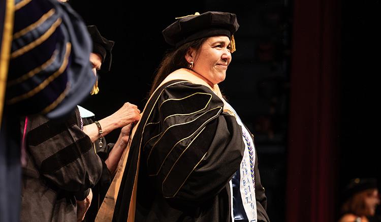 Jessica Delgado is hooded by her adviser at the 2026 UCSF School of Nursing Commencement at the Palace of Fine Arts Theatre. 