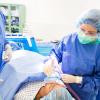 CRNA provides anesthesia to a patient in a surgery room