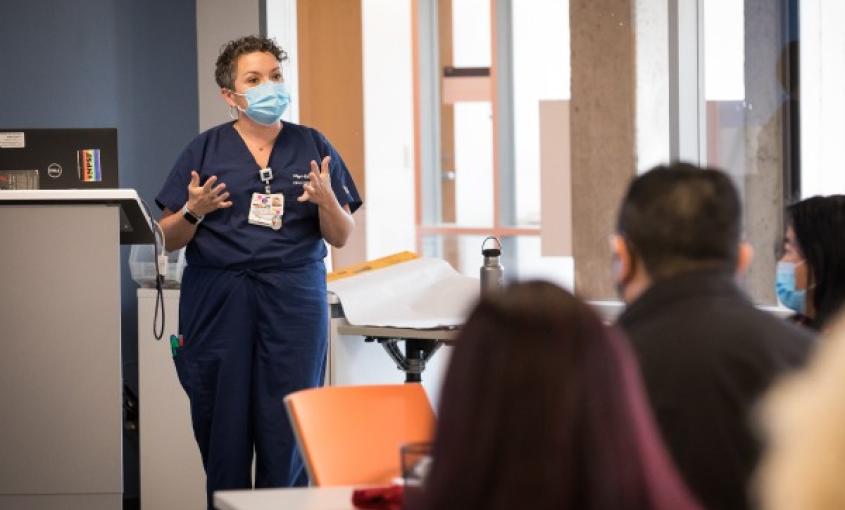 Instructor stands at front of class, teaching students.