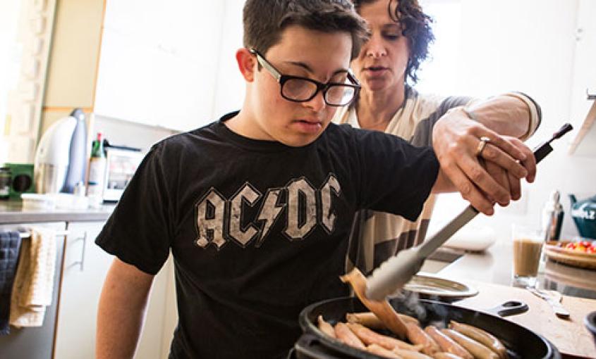 Seventeen-year-old Eli Cooper gets a cooking lesson from his mother, Jennifer (photo by Elisabeth Fall).