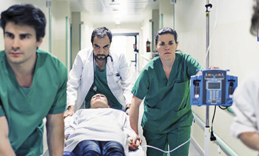 Nurses move patient on a hospital gurney.
