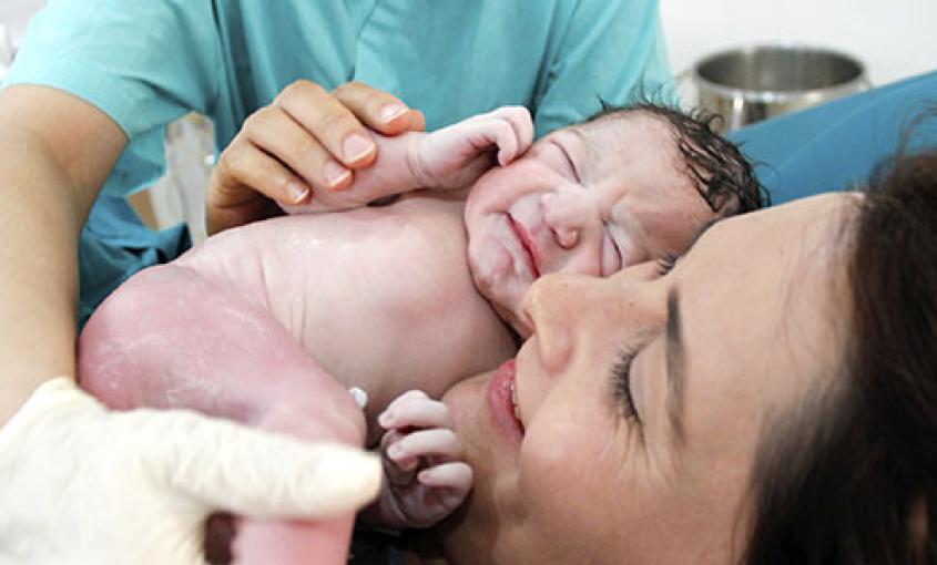 A nurse places an infant on its mother's chest.