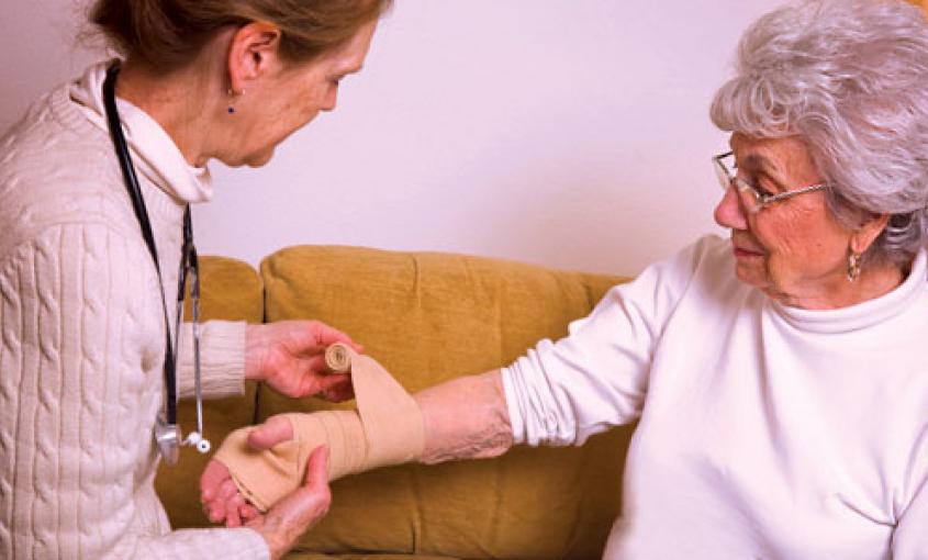 Nurse wraps wrist of patient with bandage.