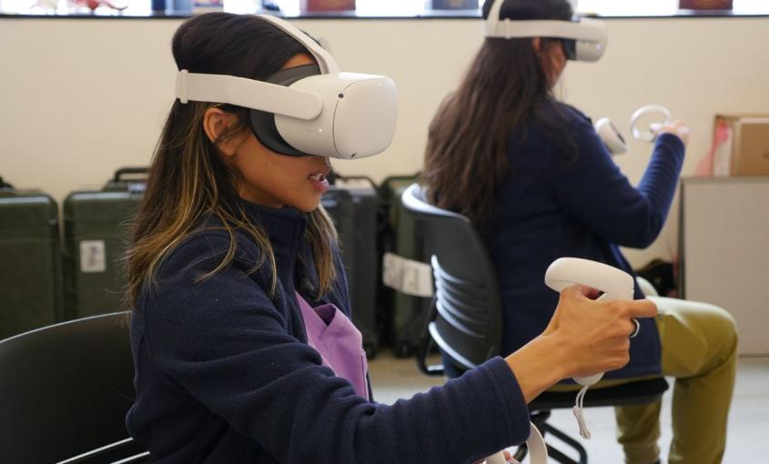 Two students wear virtual reality headsets while sitting in a classroom 
