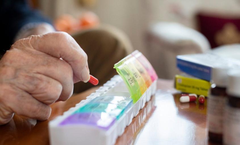 Hand placing pills in a pill organizer