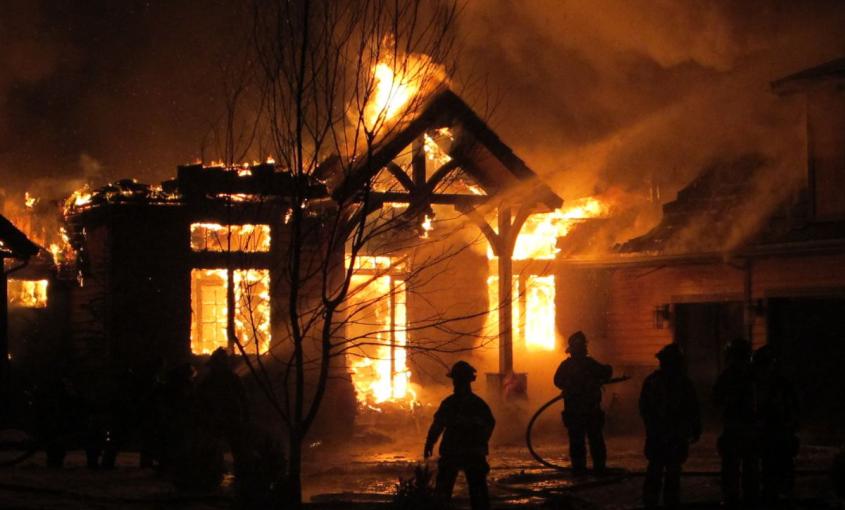 Firefighters spray water on a house that is on fire.