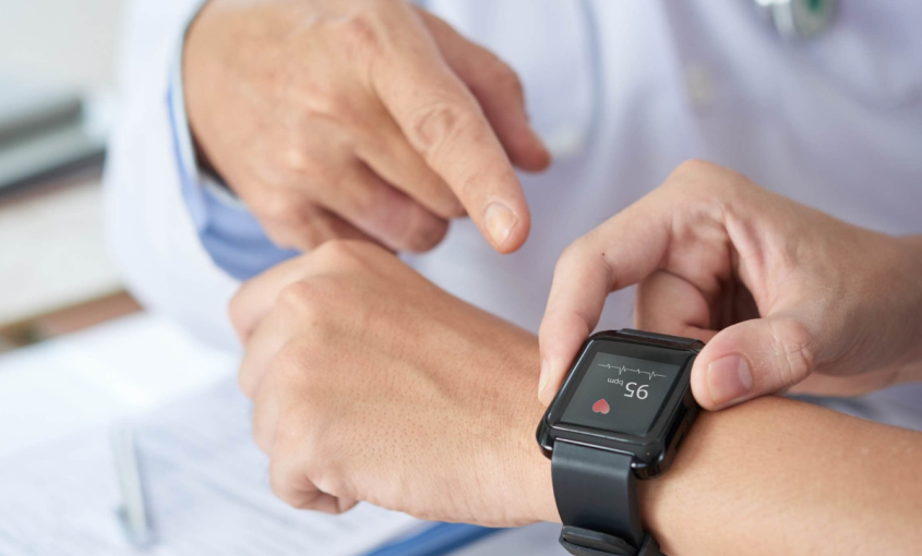 Healthcare provider points at someone's wrist that is adorned with a wearable fitness tracker.